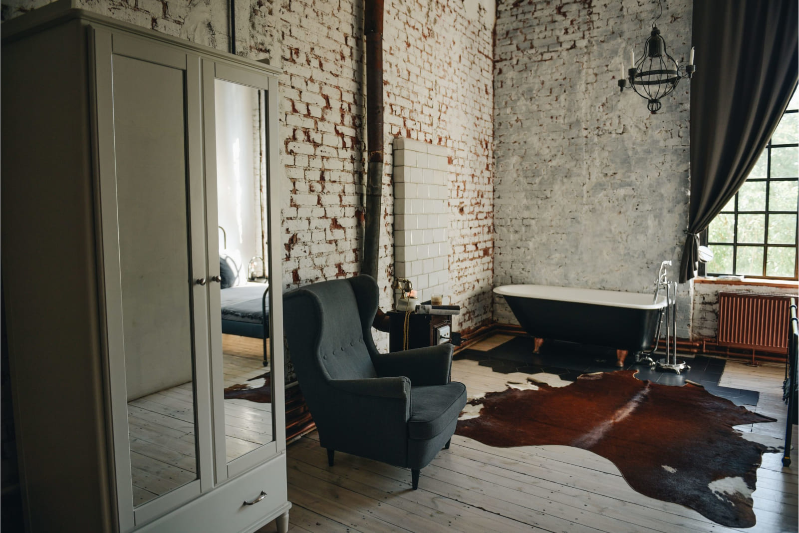 Film set room with a cast iron bathtub by the bed and white brick