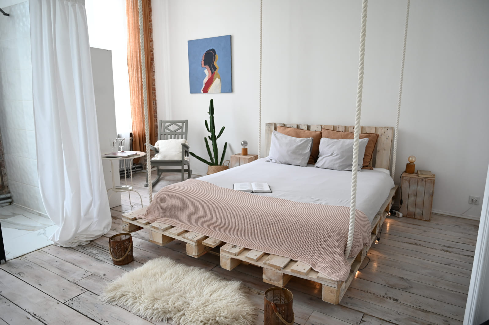 Bright white room with a bed suspended on ropes